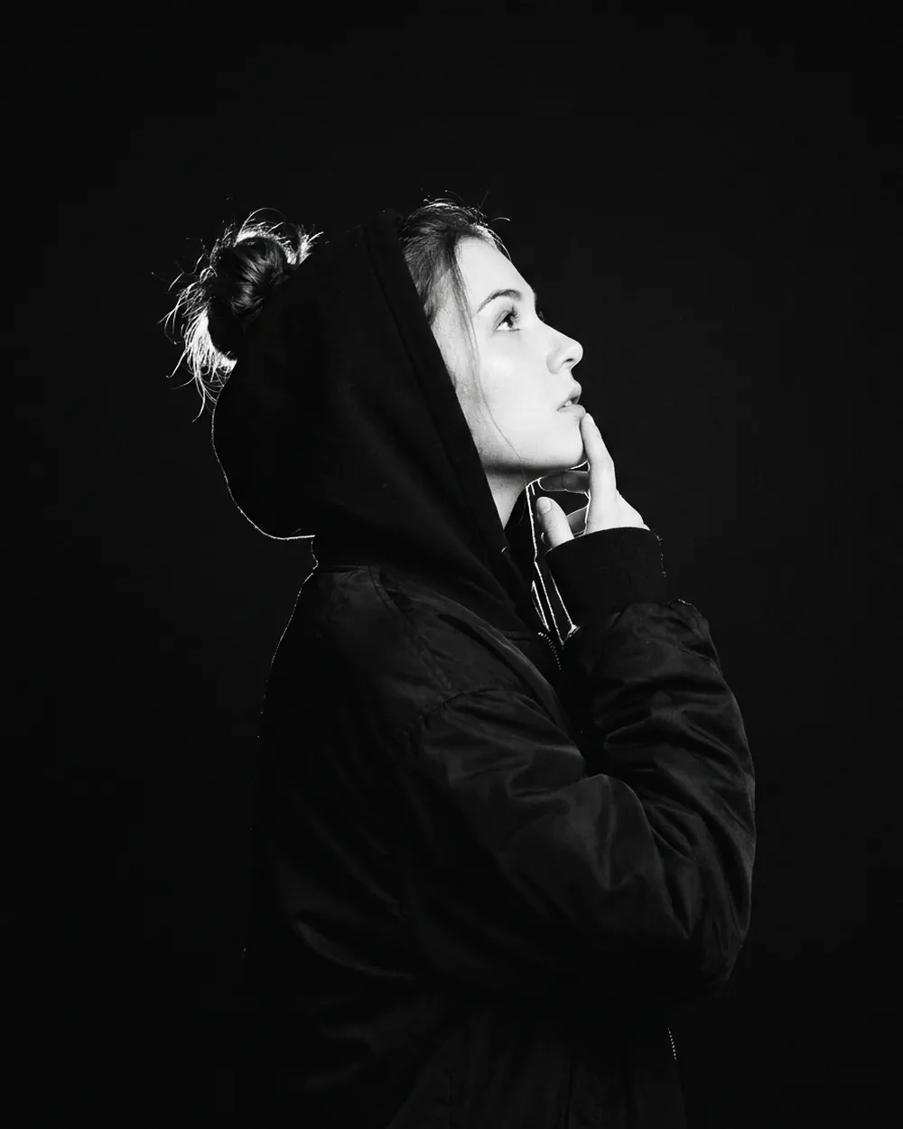 A hooded Moontian looking up, hand at the chin