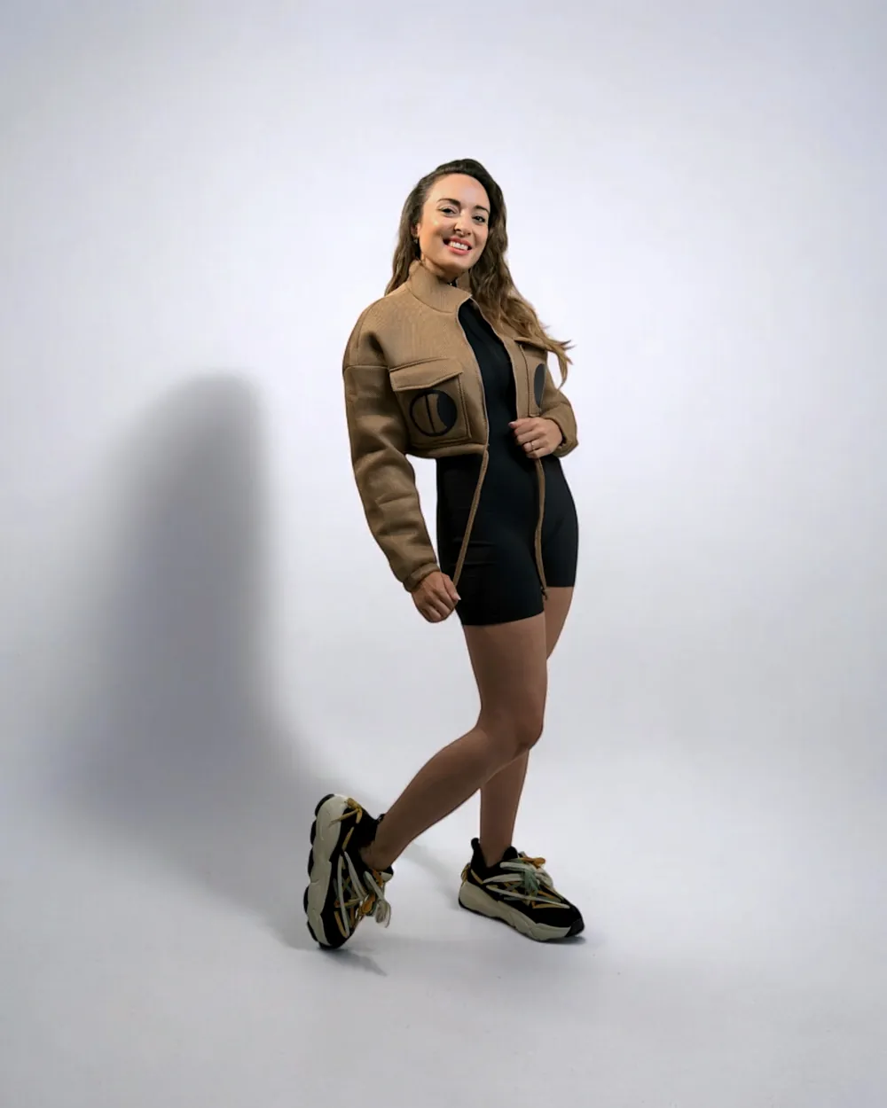 A Moontian in a cropped jacket and trainers, mid-stride