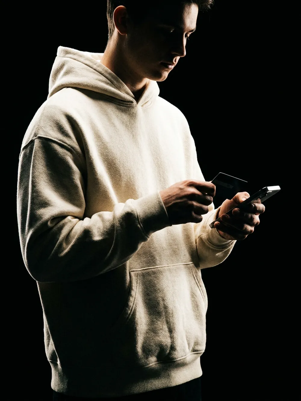 A Moontian in a hoodie lit by a phone screen