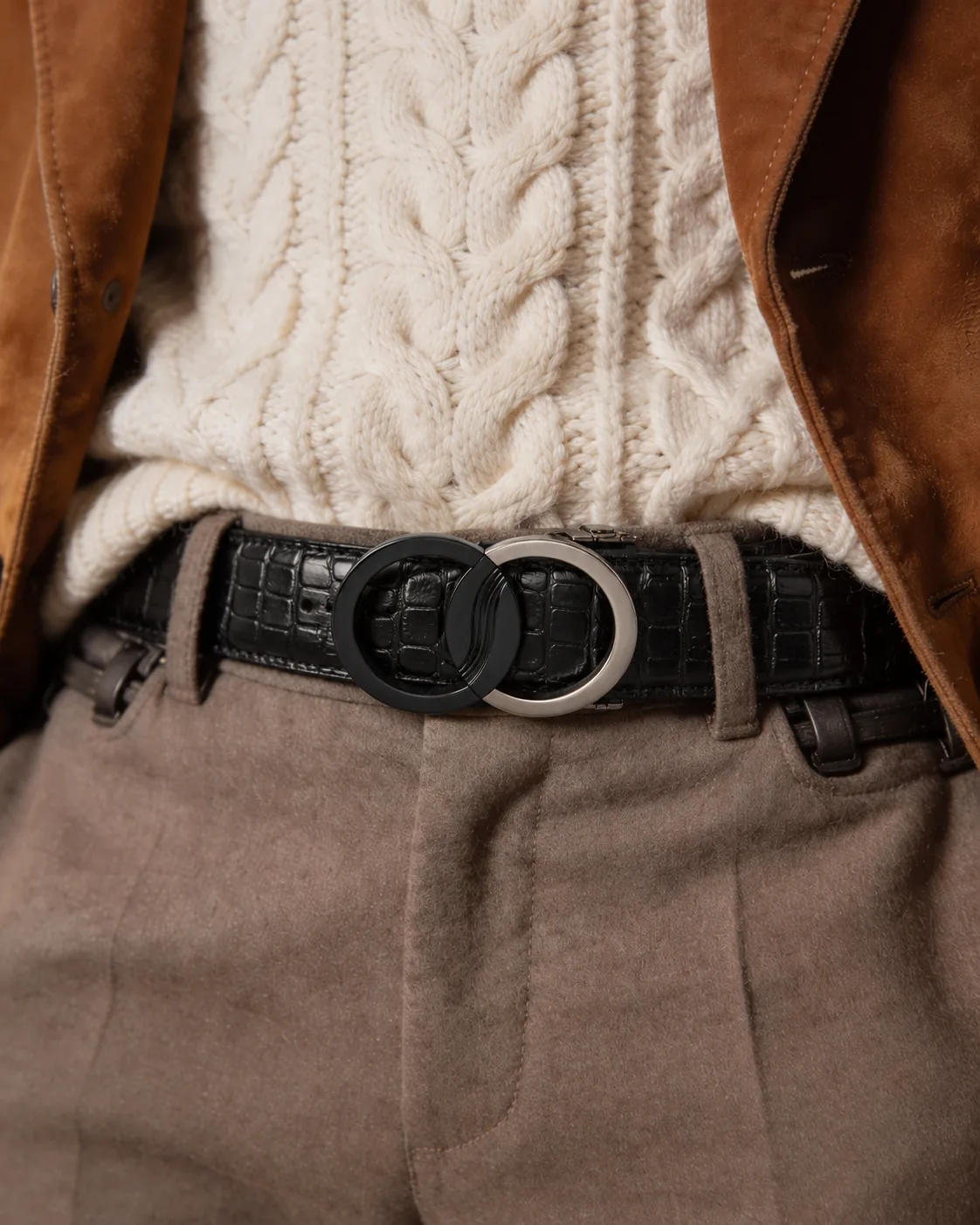 Eclipse Emblem belt: black croc-grain leather with a matte black and silver dual moon buckle, worn with a cream cable knit, suede jacket and taupe trousers